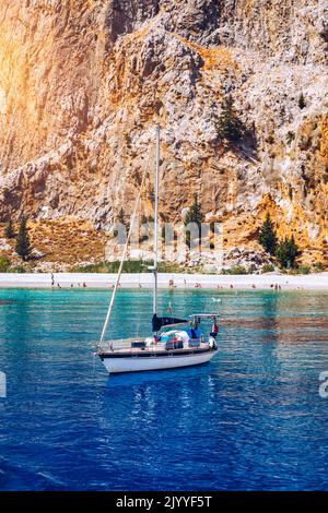 Yacht ancorante in acque cristalline turchesi di fronte all'isola tropicale, stile di vita alternativo, vivendo su una barca. Vista dello yacht all'ancora Foto Stock