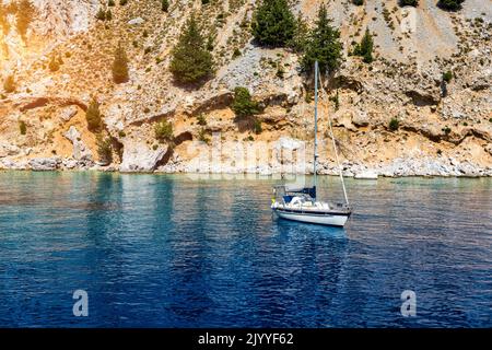 Baia di San Giorgio sull'isola di Symi, sosta popolare per i turisti per fare una nuotata nelle acque turchesi, isola di Symi, Grecia. Barca a vela al Symi Foto Stock