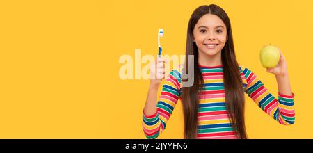 Seguire l'igiene orale. Ragazza felice tenere mela e spazzolino da denti. Igiene orale. Cura dentale. Banner di bambina con pennello denti, ritratto studio, intestazione Foto Stock