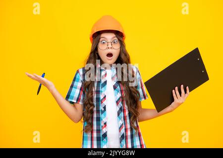 Scioccato sorpresa ragazza adolescente. Bambino pittore adolescente in casco con clipboard. Bambino in elmetto. Ingegnere di capretto sul luogo di costruzione. Ristrutturazione e. Foto Stock