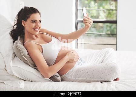 Ricordi del congedo di maternità. Una donna incinta che prende un selfie a casa. Foto Stock