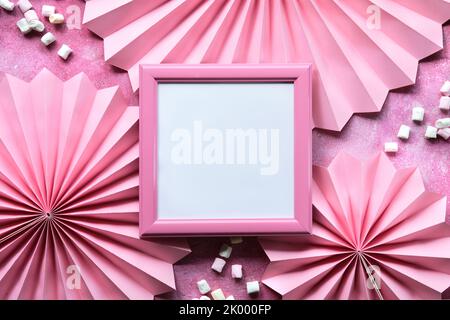 Ventole di carta rosa, marshmallow e cornice bianca. Disposizione piatta, vista dall'alto sulla cornice dell'immagine. Spazio di copia, posizionare il testo in uno spazio quadrato bianco. Foto Stock