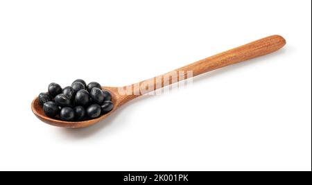 Soia nera e cucchiaio di legno su fondo bianco. Fagioli di soia neri. Foto Stock