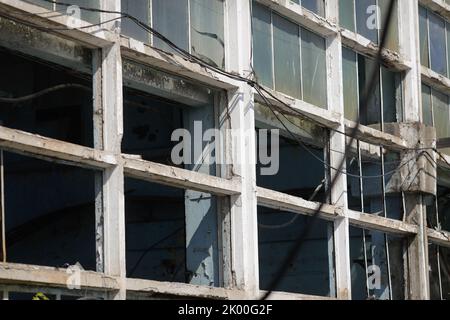 Muri e finestre rotti in un edificio industriale abbandonato. Foto Stock