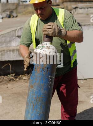 Bucarest, Romania - 8 settembre 2022: Profondità di campo poco profonda (fuoco selettivo) dettagli con un lavoratore che gestisce un serbatoio di ossigeno industriale. Foto Stock