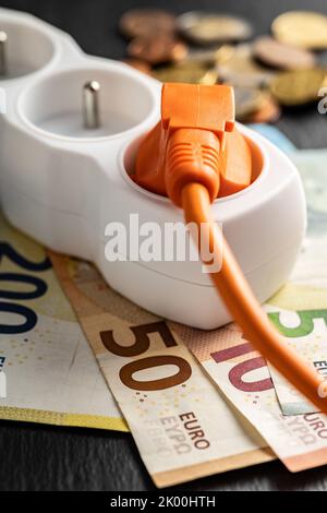 Spina elettrica, presa e denaro in euro. Concetto di aumento dei prezzi elettrici. Foto Stock