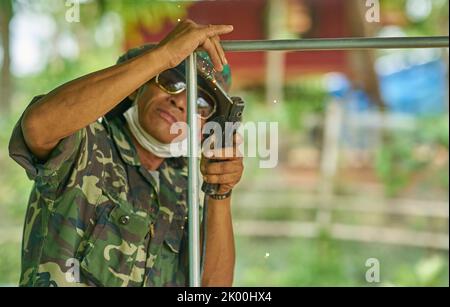 Un saldatore al lavoro all'aperto con uno sfondo verde lussureggiante. Foto Stock