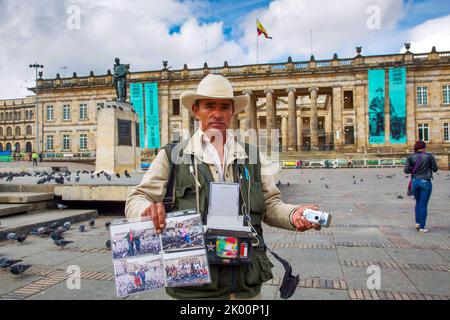 Colombia, Bogotà, in Plaza de Bolivar di fronte al Capitolio Nacional un fotograpatore sta raffigurando le persone di fronte a questo edificio e con un mobil Foto Stock