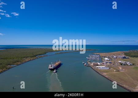 Vista aerea di una nave da carico in un fiume Port Bundaberg Queensland Australia vicino a strutture costiere sotto cieli azzurri Foto Stock