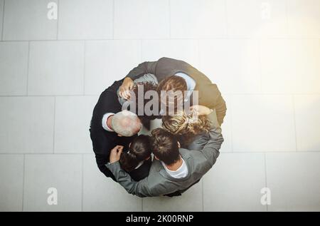 Nel huddle. Colpo ad angolo alto di un gruppo di uomini d'affari in piedi in una huddle. Foto Stock