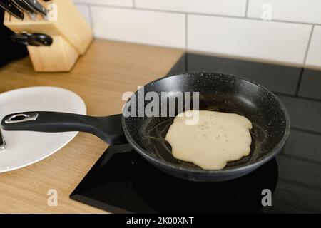 cucinare una frittella in una padella su una stufa Foto Stock