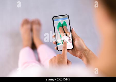 Donna che prova le scarpe con tacco alto virtuale in negozio o nell'app AR del negozio Foto Stock