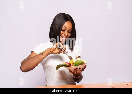 bella giovane donna africana che mangia frutta Foto Stock