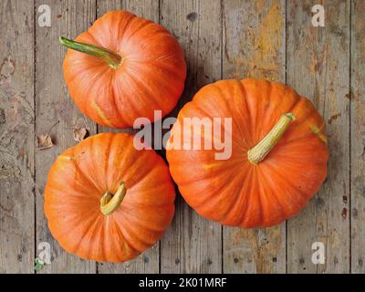 Tre zucche fresche e foglie autunnali su tavolo di legno invecchiato. Foto Stock