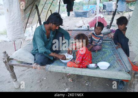 Jamshoro. 8th Set, 2022. Un uomo colpito da alluvioni con bambini mangia cibo in una tenda di fortuna nel distretto di Jamshoro, nella provincia pakistana di Sindh, il 8 settembre 2022. Almeno 36 persone sono state uccise in pesanti inondazioni provocate dalla pioggia di monsoni nelle ultime 24 ore in Pakistan, ha affermato la National Disaster Management Authority (NDMA). Credit: Str/Xinhua/Alamy Live News Foto Stock