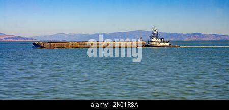 Un rimorchiatore spinge una chiatta piena di aggregato attraverso la baia di San Francisco in California, Stati Uniti Foto Stock