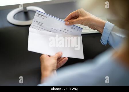 Assegno di retribuzione nella busta. Donna mano che tiene il controllo di paga Foto Stock