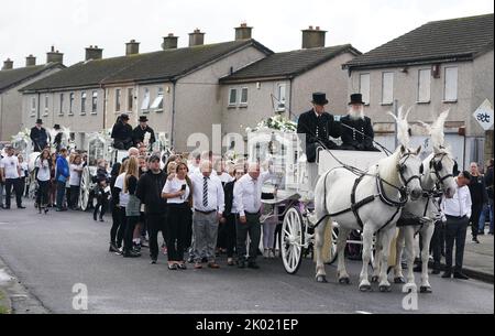 I pianori camminano dietro tre hearse trainate da cavalli che trasportano le bare di Lisa Cash, 18, e dei suoi fratelli gemelli di otto anni, Christy e Chelsea Cawley, dopo il loro servizio funerario alla St Aidan's Church, Brookfield, Tallaght. Data immagine: Venerdì 9 settembre 2022. Foto Stock