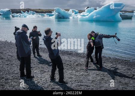 Turisti in posa per le foto da iceberg nella laguna glaciale di Jokulsarlon, Islanda Foto Stock