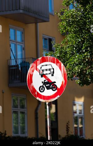 Rosso e bianco, nessun cartello per veicoli a motore sulla strada della città con edificio giallo sullo sfondo Foto Stock