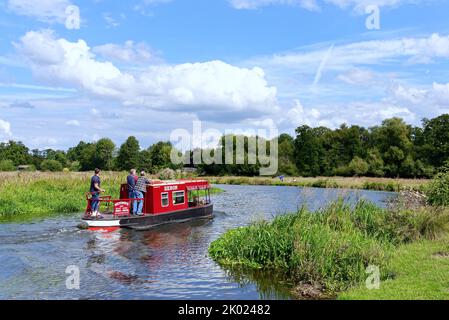 Una barca stretta solita che naviga sul canale di navigazione River Wey vicino Ripley in un giorno estivo Surrey Inghilterra UK Foto Stock