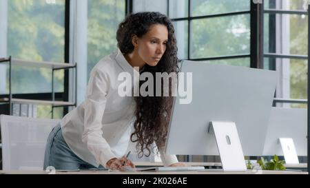 Busy riuscito businesswoman che lavora in ufficio che scrive i dati dal calcolatore il direttore creativo professionale femminile bello sviluppa il programma per Foto Stock