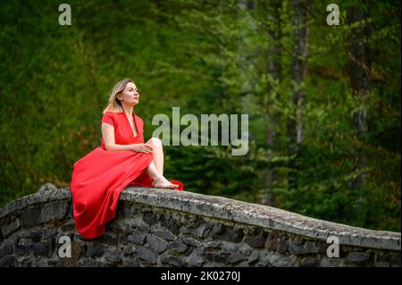 Ponte ad arco in pietra nel parco, ponte pedonale sul fiume a cascata, una donna che giace sul ponte, vista aerea, parchi di Ucraina. Foto Stock