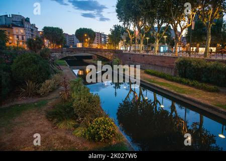 Passeggiata Nicolo sadi Carnot e erba verde accanto al torrente ( bassa) e aiuole di fiori vicino all'acqua - sorprendente fioritura includono viola Foto Stock