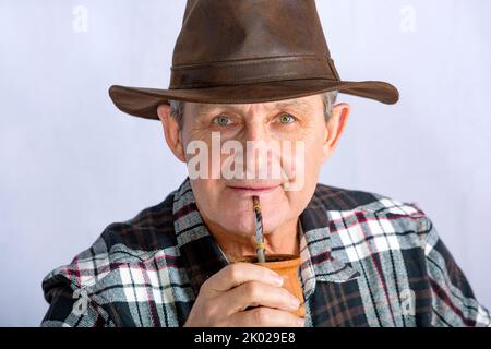 Uomo anziano dagli occhi chiari che beve l'infusione tipica in Argentina chiamata Mate Foto Stock