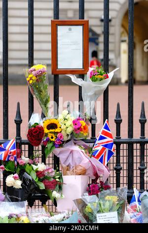 Buckingham Palace, Londra, Regno Unito – Venerdì 9th settembre 2022 – Fiori e bandiere ora circondano l'avviso ufficiale di morte della Regina Elisabetta II fuori Buckingham Palace. Foto Steven Maggio / Alamy Live News Foto Stock