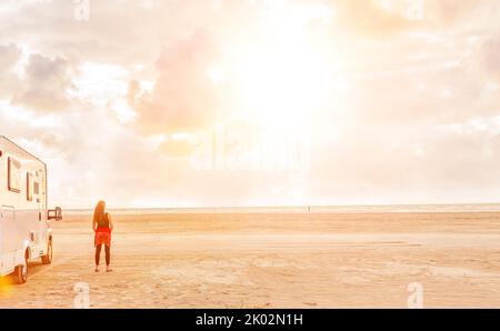 Donna accanto al camper sulla spiaggia Foto Stock