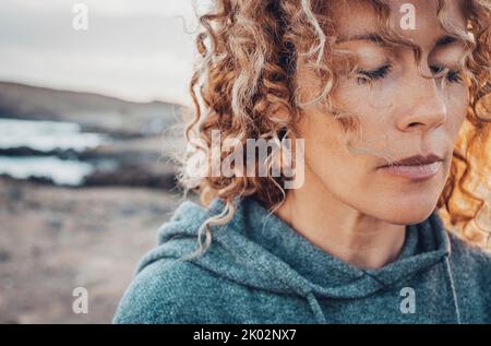 Primo piano ritratto del volto della donna con gli occhi chiusi. Concetto di sensazione e sensazioni. Le donne in meditazione o attività di consapevolezza. Solitudine ed equilibrio di vita interiore Foto Stock