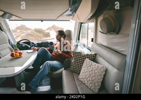 Vista interna di una donna che si gode il tramonto sulla porta del camper. Viaggi e wanderlust stile di vita moderno concetto di persone alla moda. Donna con cappelli vita indipendente e libertà Foto Stock
