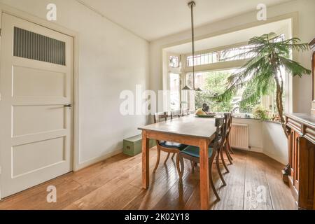 Semplice tavolo con sedie situato sotto un elegante lampadario vicino alle porte in un elegante sala da pranzo Foto Stock