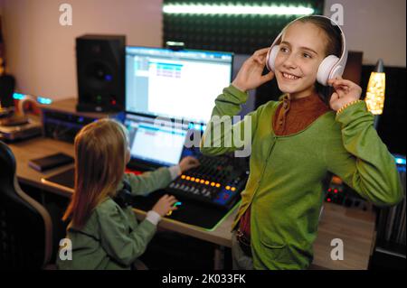 I bambini in studio di registrazione si concentrano sull'ascolto di musica in cuffia Foto Stock