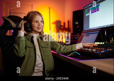 Giovane ingegnere audio che mixa il suono in casa di produzione Foto Stock