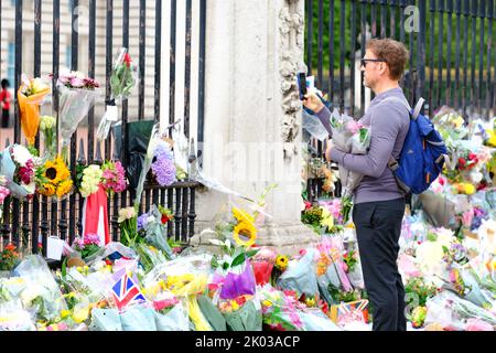 Buckingham Palace, Londra, Regno Unito – Venerdì 9th settembre 2022 – Un uomo vede i numerosi tributi floreali fuori Buckingham Palace mentre la Gran Bretagna piange la morte della Regina Elisabetta II Foto Steven Maggio / Alamy Live News Foto Stock