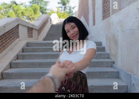 Giovane donna giapponese asiatica felice e bella in posa all'aperto felice e allegro in città incinta mostrando il suo ventre orgoglioso sorridendo in gravidanza an Foto Stock