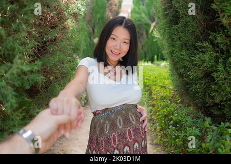 Giovane donna giapponese asiatica felice e bella in posa all'aperto felice e allegro in città incinta mostrando il suo ventre orgoglioso sorridendo in gravidanza an Foto Stock