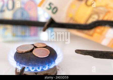 Fornello a gas, fiamma a gas, piccolo cambio, banconote dietro di esso Foto Stock