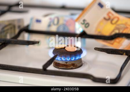 Fornello a gas, fiamma a gas, piccolo cambio, banconote dietro di esso Foto Stock