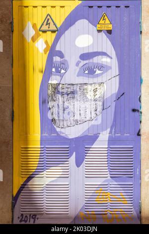 Spagna, Isole Baleari, Maiorca, Palma de Mallorca. Murales su una sottostazione elettrica raffigurante il volto di una donna a cui è stata aggiunta una maschera chirurgica in tempi di covid / pandemic / covid-19 Foto Stock