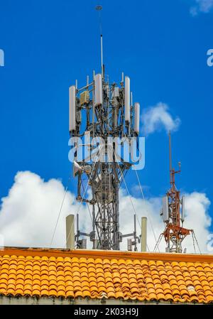 La torre bianca rossa del 5G con la radiazione di sfondo blu del cielo ci uccide a Playa del Carmen in Messico. Foto Stock