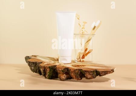 Set di prodotti biologici per la cura orale. Composizione ecologica con dentifricio, spazzolini in vaso di vetro su un podio di legno. Igiene naturale dei denti e de Foto Stock