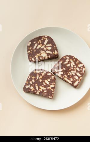 Dessert tradizionale portoghese Salame de Chocolate su sfondo beige in stile minimal. Menu di panetteria del ristorante Foto Stock