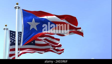 Bandiera di Porto Rico che sventola nel vento con la bandiera degli Stati Uniti in una giornata limpida. Puerto Rico è un'isola caraibica e territorio non incorporato di t Foto Stock