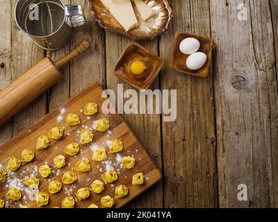 Gnocchi crudi fatti in casa su un tagliere, ingredienti su uno sfondo di legno. Processo di cottura. Ricette per la cucina casalinga. Cucinare piatti di carne. Famiglia Foto Stock