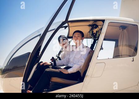 Pilota cinese che insegna a far funzionare il quadro di comando nel cockpit Foto Stock