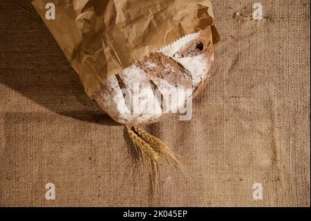 Panetteria artigianale. Vista dall'alto. Pane di pasta madre e spighe di grano su tavola ricoperte di tovaglia di lino. Cucina casalinga. Foto Stock