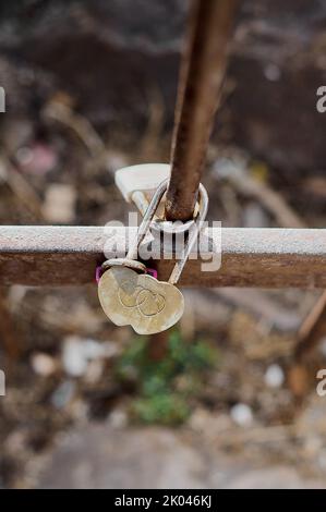 Lucchetto a forma di cuore con due cuori intrecciati all'interno e attaccati a una ringhiera di ferro, con messa a fuoco selettiva sul cuore e spazio libero nella foto Foto Stock